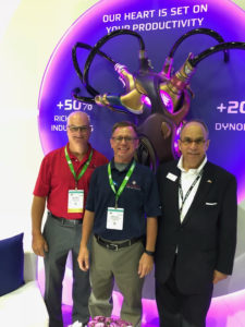 Three Richards' employees pose in front of a sign at the IMTS Show